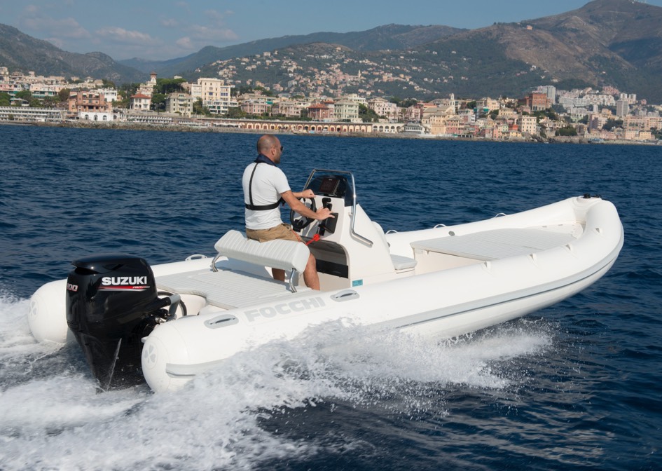 suzuki outboard anchored in a small white inflatable boat running in on a shallow water