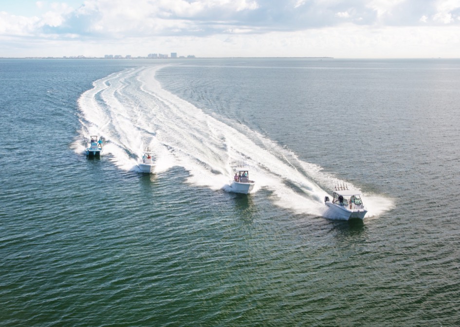 Four white boats race in an ocean.