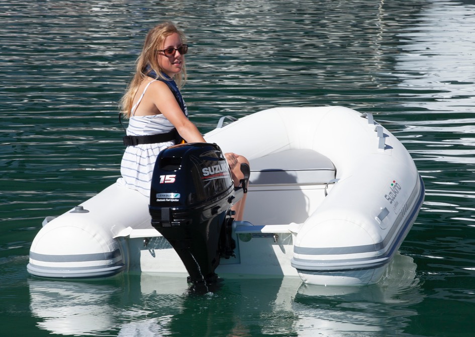 small white inflatable boat anchored with a suzuki boat engine